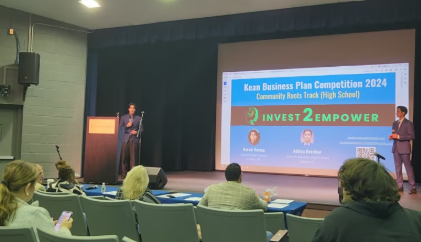 Karan Verma and Aditya Herekar presenting Invest2Empower on stage at the 2024 Kean Business Plan Competition, Community Roots Track