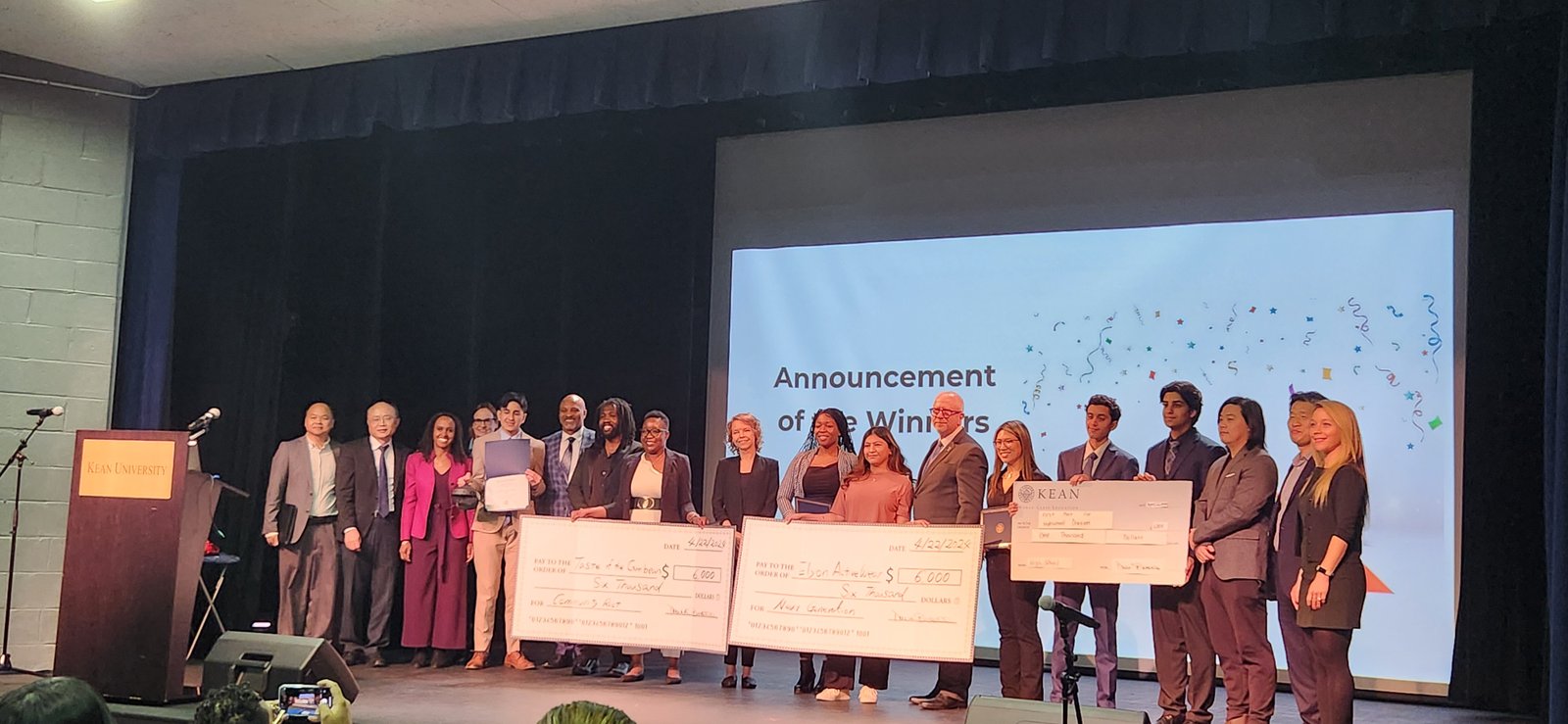 All winners of the 2024 Kean Business Plan Competition on stage with their checks, Invest2Empower at right